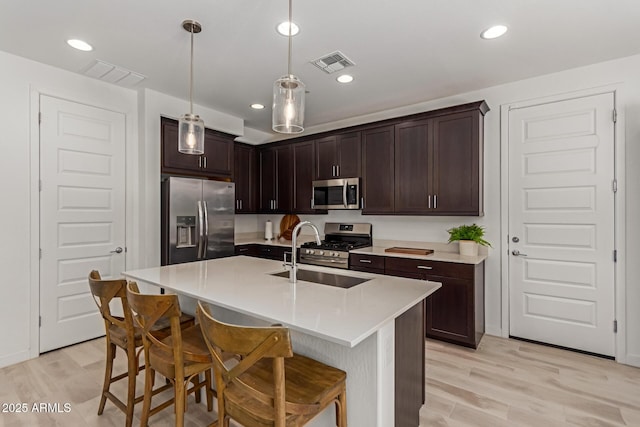 656 S Owl Dr, Gilbert, AZ 85296 - kitchen with stainless steel appliances, a sink, light wood-style flooring, dark brown cabinetry, and recessed lighting