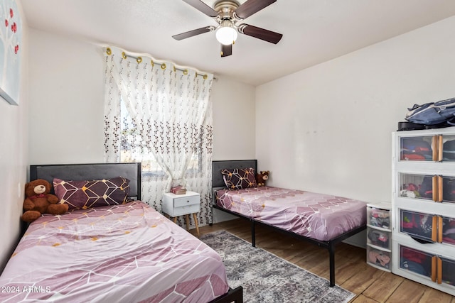 bedroom featuring hardwood / wood-style flooring, ceiling fan, and multiple windows