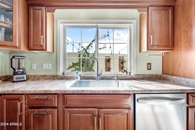 kitchen with light stone counters, stainless steel dishwasher, and sink