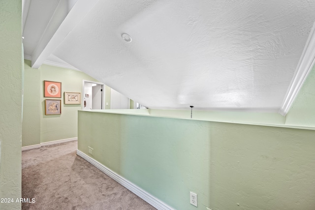 hallway with a textured ceiling, lofted ceiling with beams, and carpet