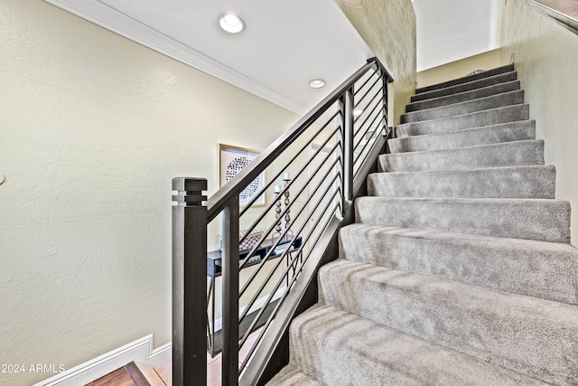 stairs with crown molding and wood-type flooring