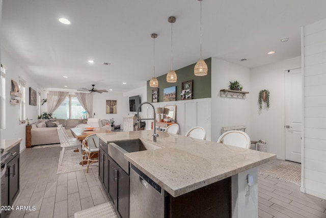 kitchen with pendant lighting, sink, ceiling fan, a center island with sink, and stainless steel dishwasher