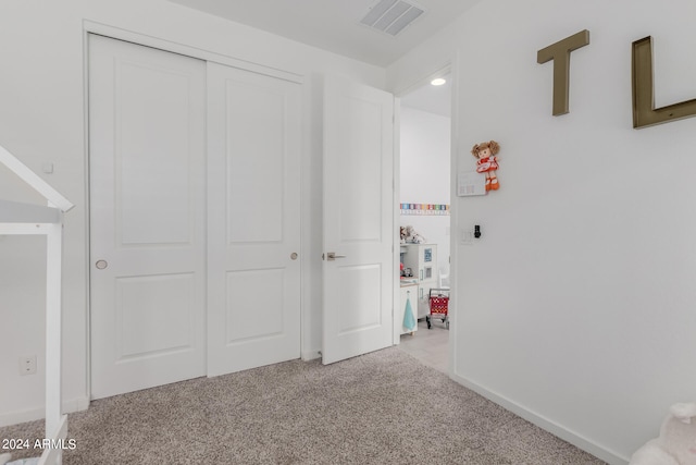 unfurnished bedroom with light colored carpet and a closet