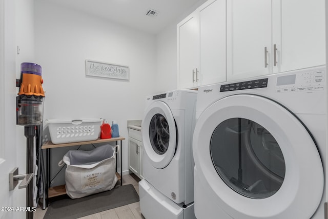 clothes washing area with cabinets and separate washer and dryer