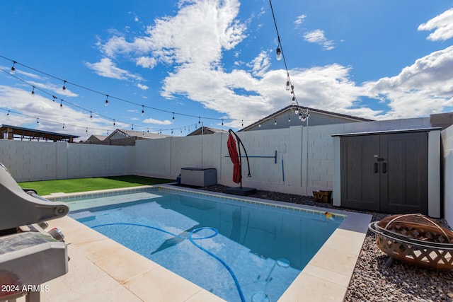 view of swimming pool featuring a storage shed and a fire pit