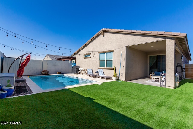 rear view of house featuring a fenced in pool, a patio area, and a lawn