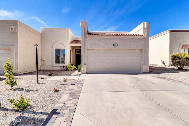 view of front of home with driveway, a tiled roof, an attached garage, and stucco siding