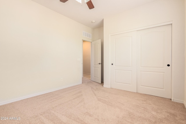 unfurnished bedroom featuring light colored carpet, a closet, and ceiling fan