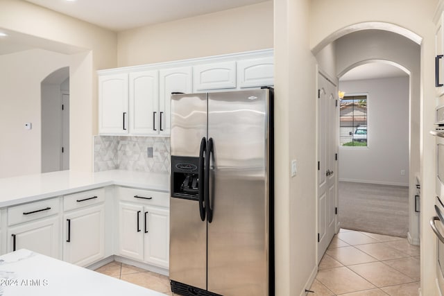 kitchen featuring tasteful backsplash, light tile floors, stainless steel fridge with ice dispenser, and white cabinetry