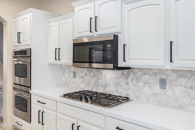 kitchen with backsplash, appliances with stainless steel finishes, and white cabinetry