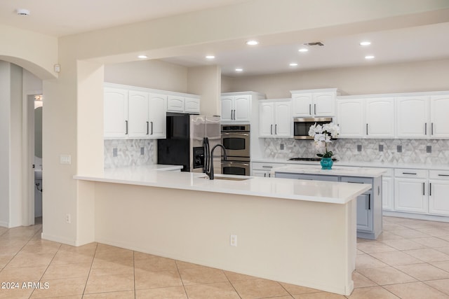 kitchen featuring stainless steel appliances, light tile flooring, tasteful backsplash, white cabinets, and sink