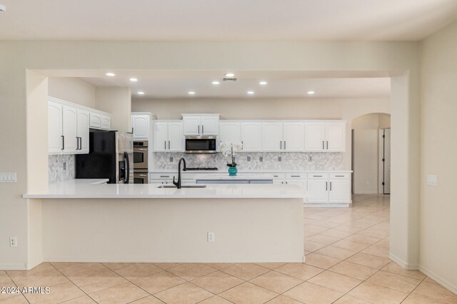 kitchen featuring tasteful backsplash, stainless steel appliances, white cabinets, and light tile floors