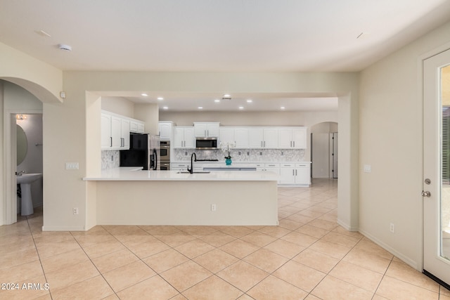 kitchen with sink, tasteful backsplash, white cabinetry, light tile flooring, and stainless steel appliances