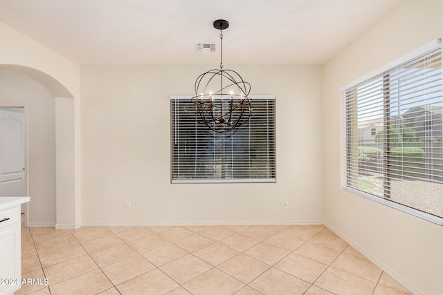 spare room with a chandelier and light tile floors