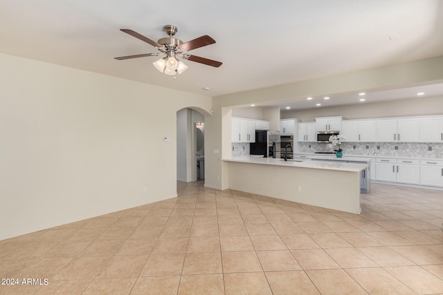 kitchen with appliances with stainless steel finishes, tasteful backsplash, light tile flooring, and white cabinetry