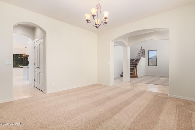 carpeted empty room with a notable chandelier