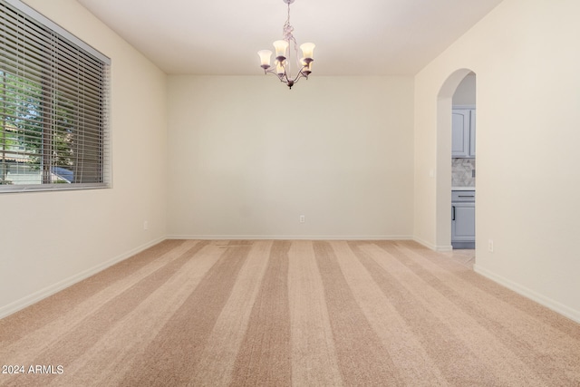 spare room with a chandelier and light carpet