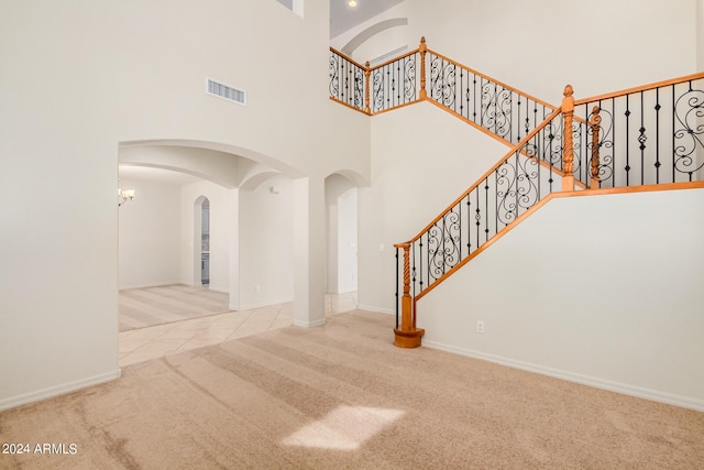 interior space featuring light colored carpet and a towering ceiling