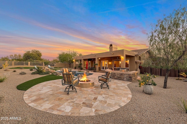 patio terrace at dusk featuring an outdoor fire pit