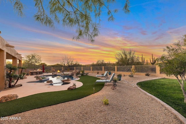 yard at dusk featuring a patio area and a fenced in pool