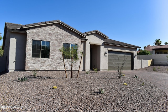 view of front of home featuring a garage, stone siding, decorative driveway, and stucco siding