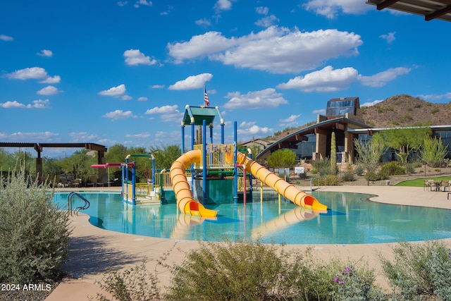 view of swimming pool featuring a playground and a water slide