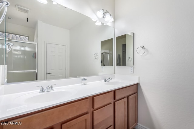 bathroom with visible vents, a sink, a shower stall, and double vanity