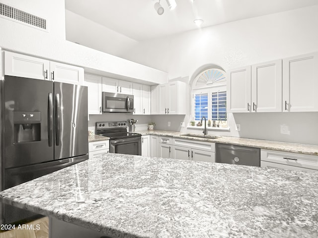 kitchen with sink, light stone countertops, white cabinets, and appliances with stainless steel finishes