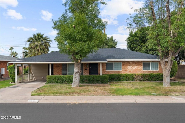 single story home with a carport, driveway, brick siding, and a front yard