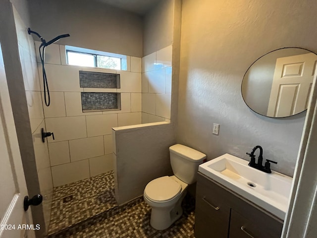 bathroom with vanity, tiled shower, toilet, and tile patterned floors