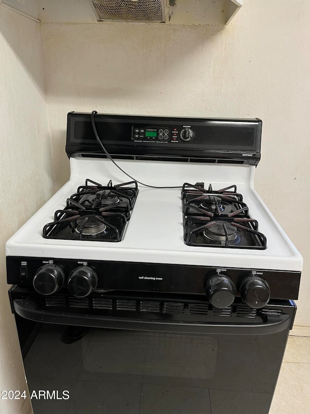 interior details featuring white gas stove and tile patterned flooring