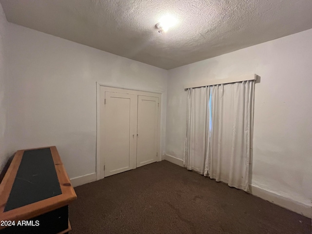 empty room with a textured ceiling and dark colored carpet