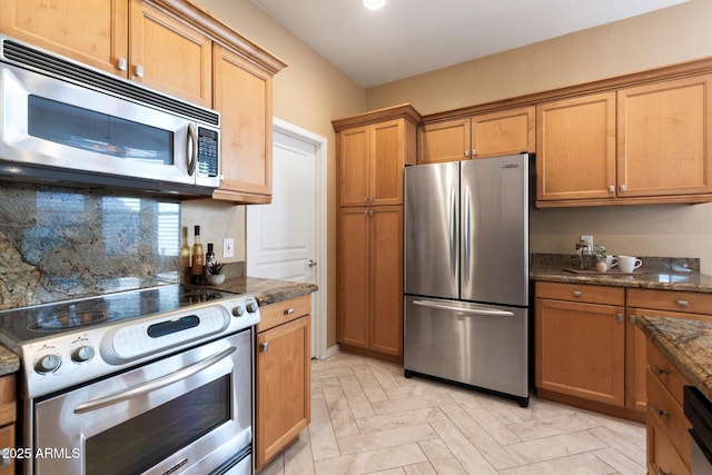 kitchen featuring dark stone counters, decorative backsplash, light parquet flooring, and stainless steel appliances