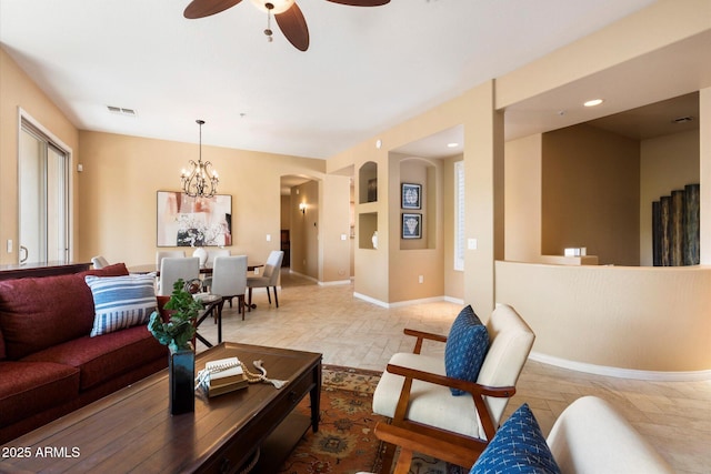 living room featuring built in shelves and ceiling fan with notable chandelier