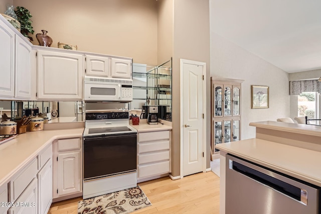 kitchen with white microwave, white cabinetry, vaulted ceiling, range with electric stovetop, and stainless steel dishwasher