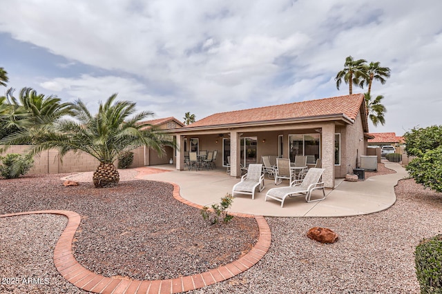 rear view of property featuring a patio area, stucco siding, and a fenced backyard