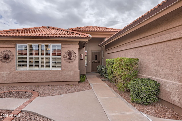 entrance to property featuring stucco siding and a tiled roof