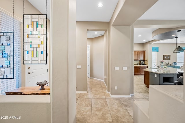 interior space featuring sink, hanging light fixtures, a kitchen island, and light tile patterned floors