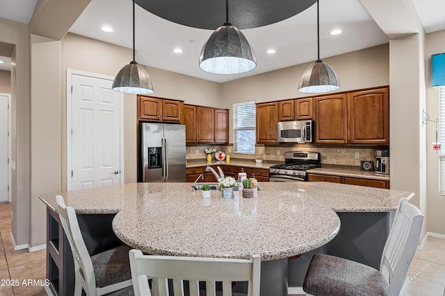 kitchen with a large island with sink, appliances with stainless steel finishes, hanging light fixtures, and a kitchen bar