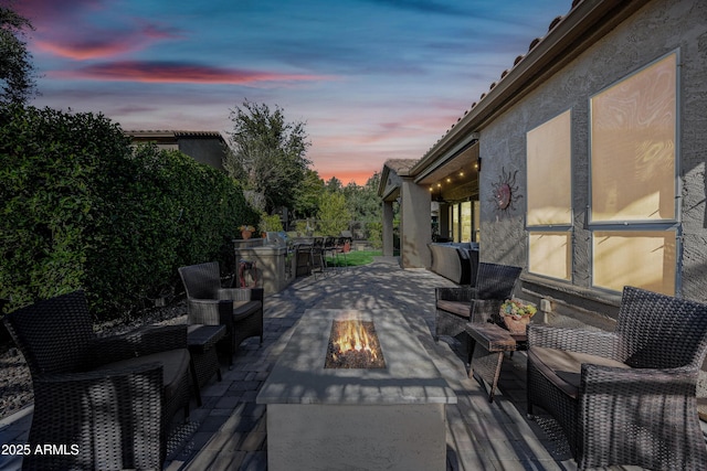 patio terrace at dusk featuring an outdoor fire pit