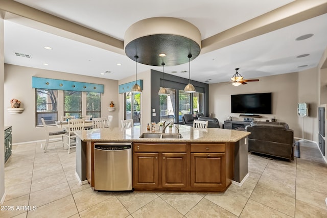 kitchen featuring sink, decorative light fixtures, dishwasher, light stone countertops, and a kitchen island with sink