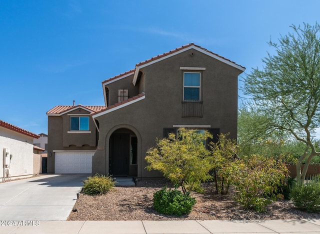 mediterranean / spanish-style house with a garage, a tile roof, concrete driveway, and stucco siding