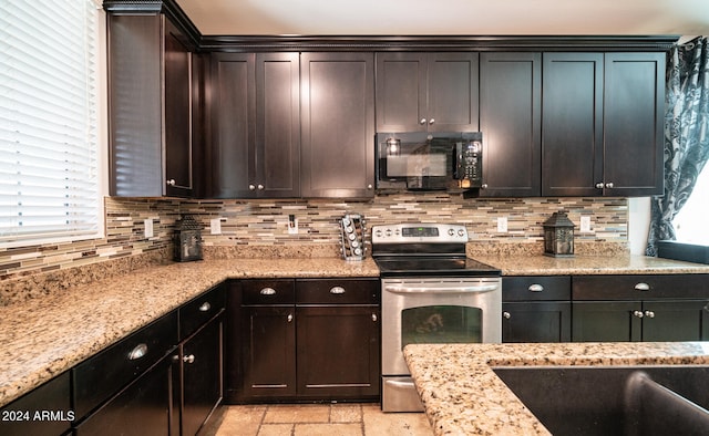 kitchen with light stone countertops, tasteful backsplash, dark brown cabinets, sink, and electric range