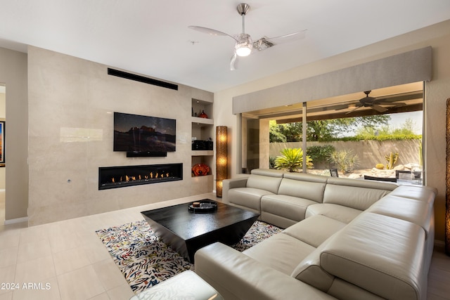 tiled living room featuring a tile fireplace, a ceiling fan, and built in features