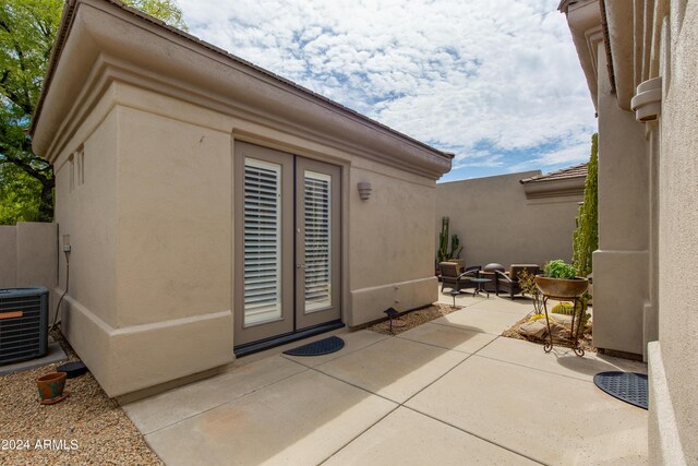 view of exterior entry with central AC unit and a patio area