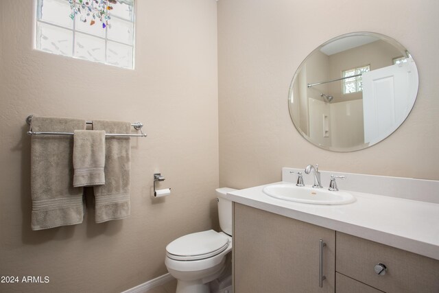 bathroom with walk in shower, toilet, and vanity