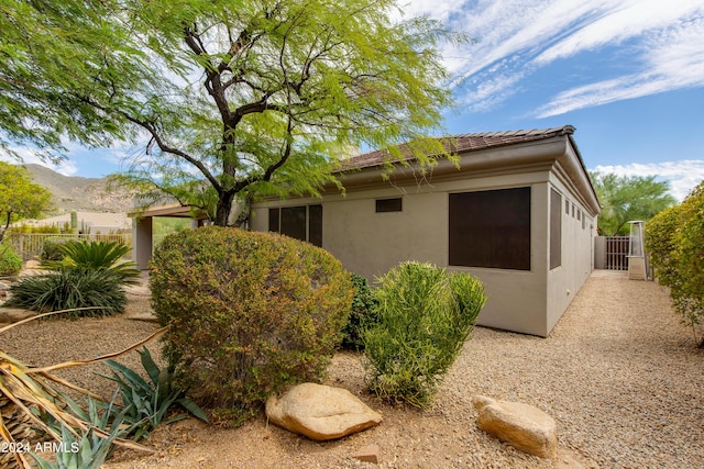 view of home's exterior featuring a tile roof, a gate, fence, and stucco siding