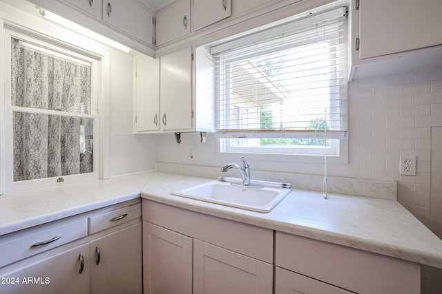 kitchen featuring sink, decorative backsplash, and white cabinetry