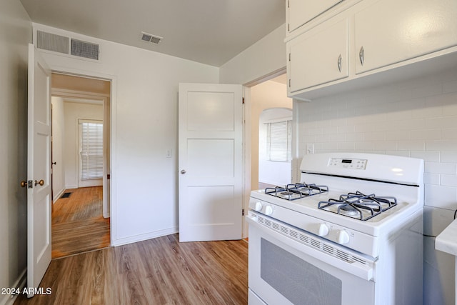 kitchen featuring light hardwood / wood-style floors, white range with gas cooktop, white cabinetry, and tasteful backsplash