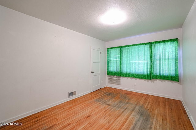 spare room with a textured ceiling and light wood-type flooring